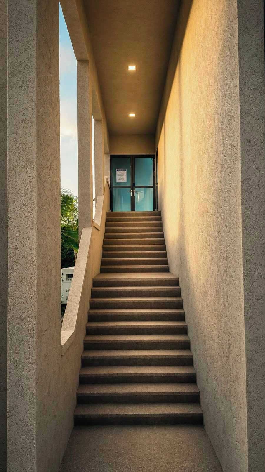 Una escalera que lleva a una puerta con un letrero, rodeada de paredes con textura.