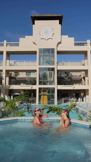 A hotel with a swimming pool, a central building with a decorative facade, and a clear blue sky. - Top-Floor 1BR | Resort Pool | Close to Eagle Beach (Noord)