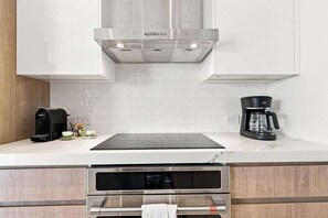 Eine moderne Küche mit eingebautem Backofen, einer Kaffeemaschine und einem Wasserkocher auf der Arbeitsfläche.