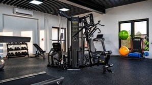 Ein Fitnessraum mit verschiedenen Trainingsgeräten, Kurzhanteln und Gymnastikbällen.