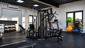 Ein Fitnessraum mit verschiedenen Trainingsgeräten, Kurzhanteln und Gymnastikbällen.