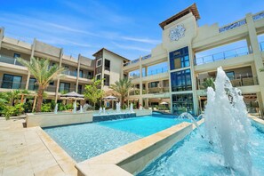 A hotel with a central pool, multiple balconies, and a fountain. - Top-Floor 1BR | Close to Aruba’s Best Beaches (Noord)