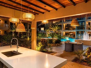A modern hotel lobby with a pool, indoor plants, and a bar area. - Top-Floor 1BR | Close to Aruba’s Best Beaches (Noord)