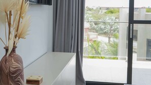 A modern living room with a white console table, a decorative vase, and a view of a balcony with a railing. - Top-Floor 1BR | Close to Aruba’s Best Beaches (Noord)