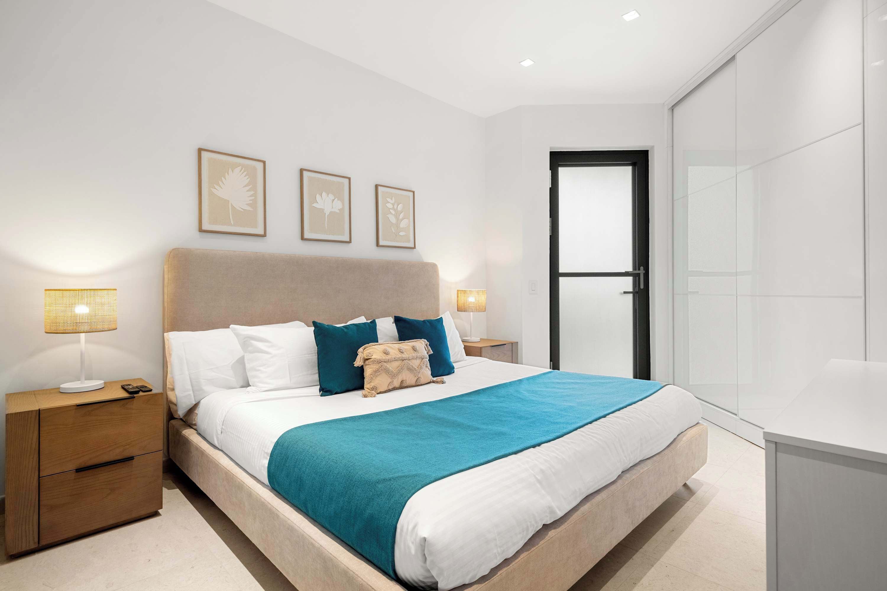 A modern bedroom with a bed, bedside tables, and a door.