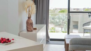 A modern living room with a dining area, a sofa, a table, and a view of the outdoors. - Top-Floor 1BR | Close to Aruba’s Best Beaches (Noord)