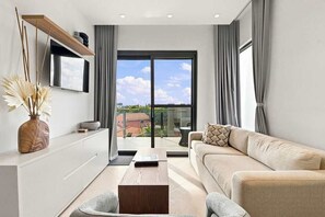 A modern living room with a sofa, coffee table, and a flat-screen TV mounted on a wall. - Top-Floor 1BR | Close to Aruba’s Best Beaches (Noord)