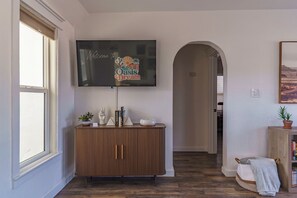 A hallway with a wooden cabinet, a television displaying 'Welcome to Oasis Dream,' and a potted plant.
