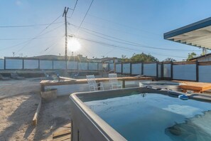 Una piscina amb un tram de fusta i gandules, envoltada per una zona tancada amb murs de metall ondulat.