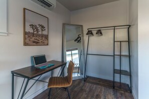 A room with a desk, chair, and a metal shelving unit.