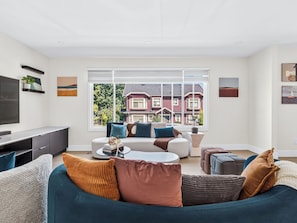 A modern living room with a large window, a flat-screen TV, and a sofa with multiple cushions. - Newly renovated 6-bedroom 6BA house with AC in central Vancouver (Vancouver)