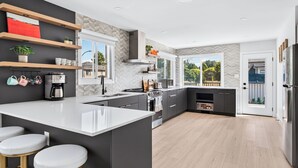 Una cocina moderna con una isla grande, taburetes de bar y vistas al exterior.
