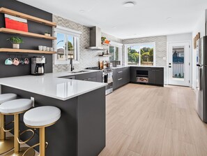 A modern kitchen with a large island, bar stools, and a view of the outdoors. - Newly renovated 6-bedroom 6BA house with AC in central Vancouver (Vancouver)