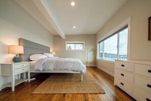 A bedroom with a bed, bedside tables, a window, and a view. - Tideline Bainbridge Luxury Waterfront (Bainbridge Island)