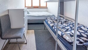 Ein kleines Zimmer mit Etagenbetten, einem Schreibtisch und einem Stuhl.