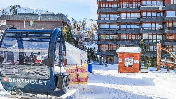 Eine Barke mit einer Seilbahn, ein Holzgebäude und ein Schild mit der Aufschrift 'THYON 2000'.