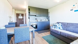 A compact living space with a dining area, kitchenette, and a sofa.