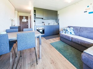 A compact living space with a dining area, kitchenette, and a sofa.