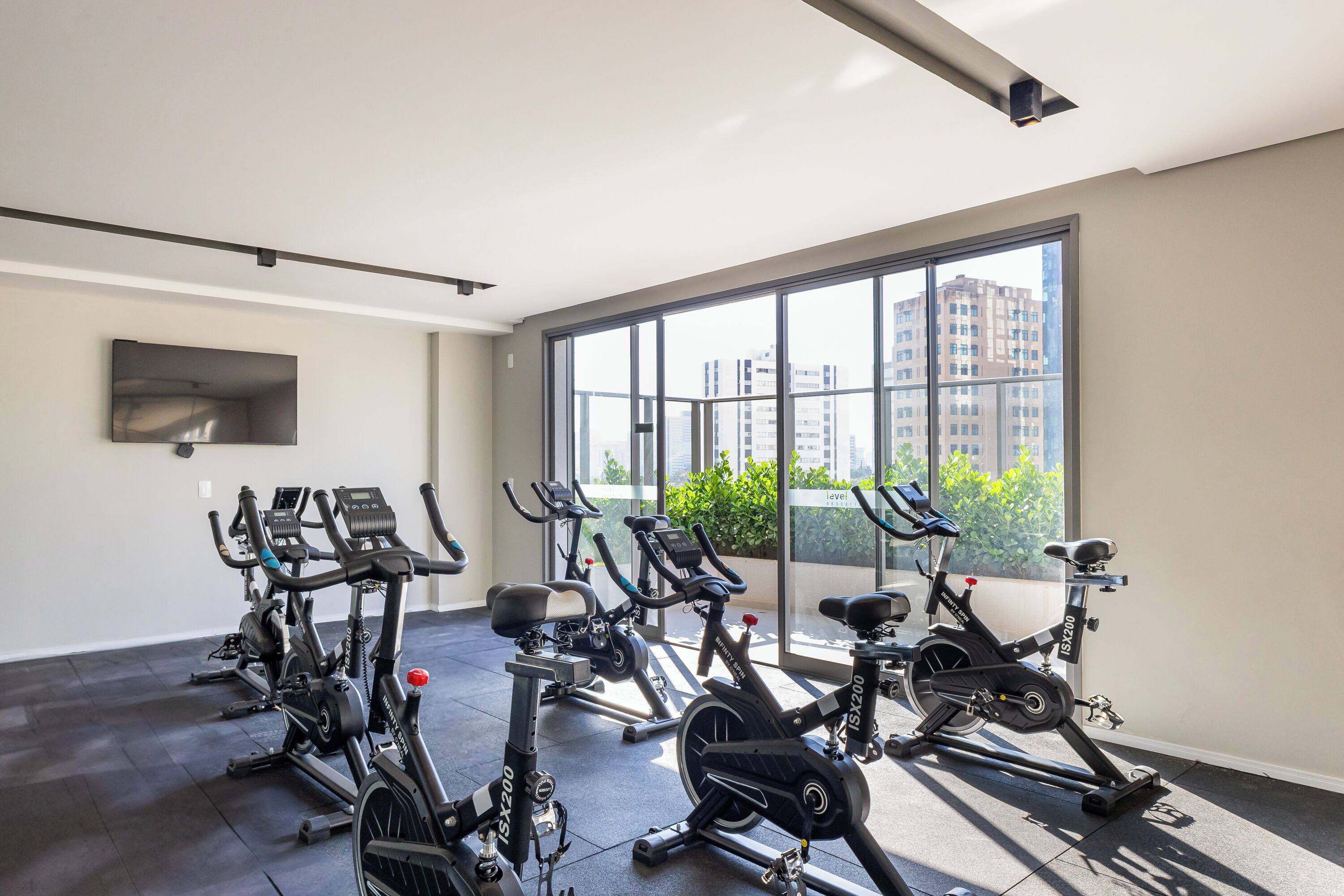 Uma academia com bicicletas ergométricas e uma grande janela com vista para a cidade.