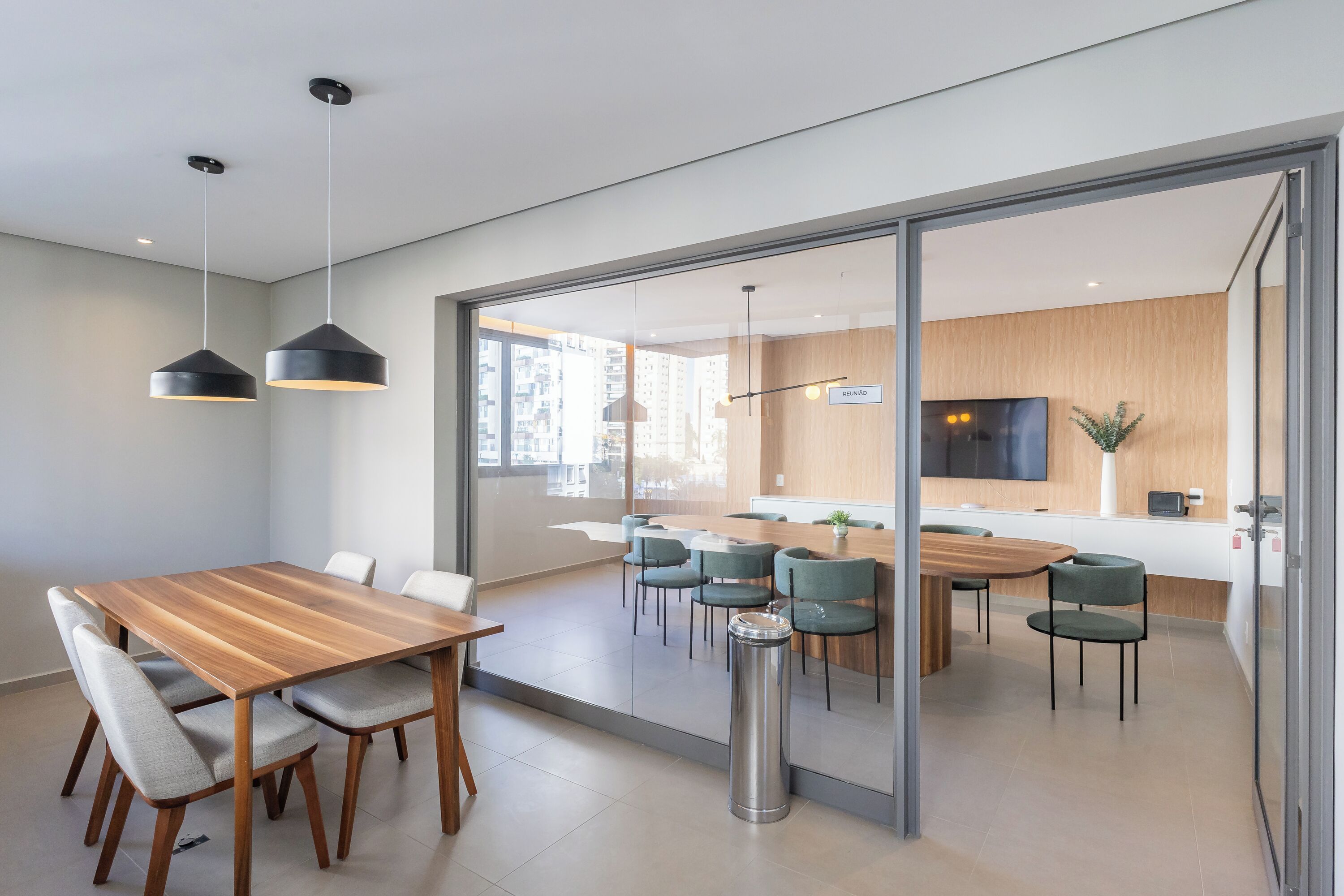 A modern meeting room with a wooden table, grey chairs, and pendant lighting.