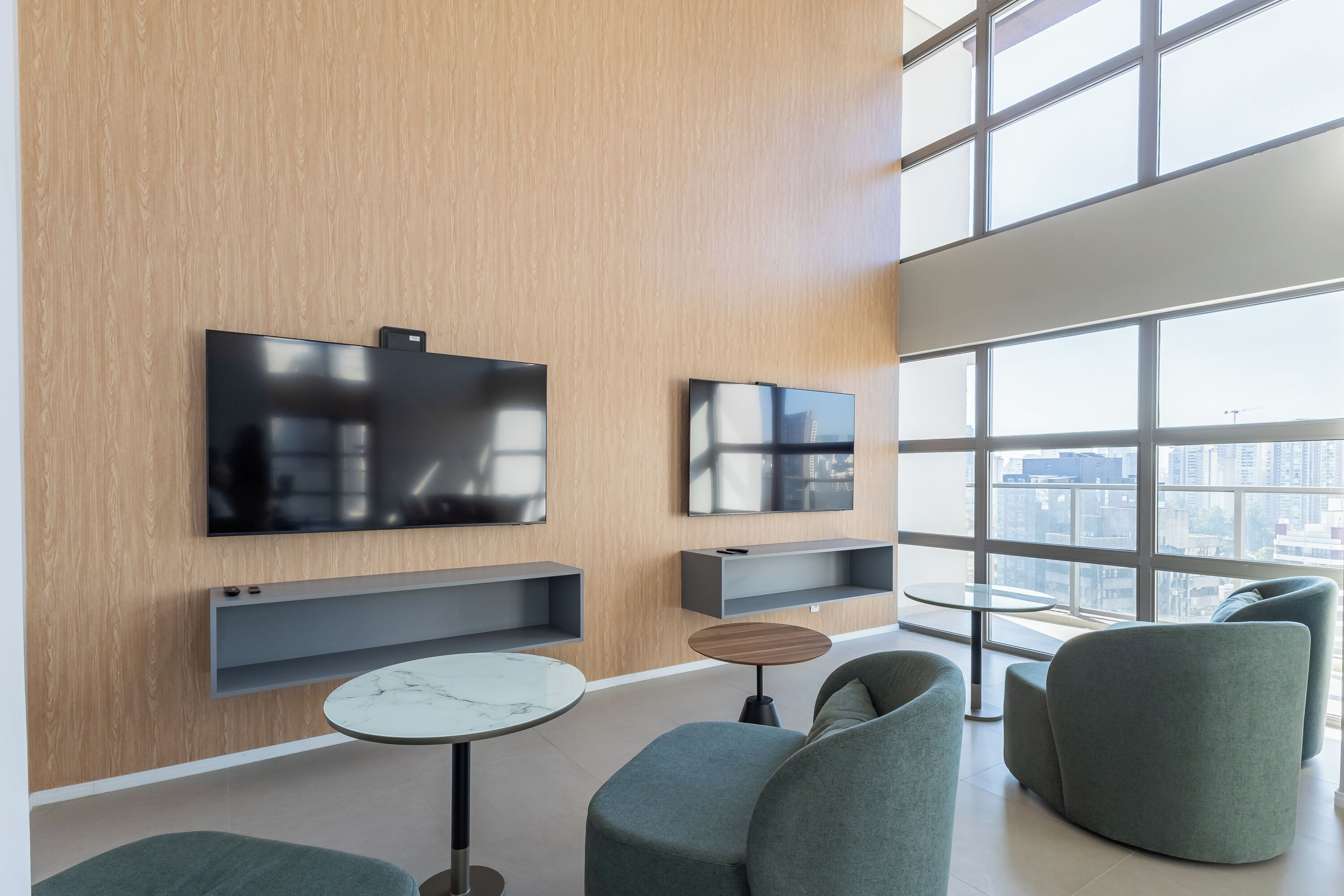 A modern living room with a large TV, comfortable seating, and a city view.