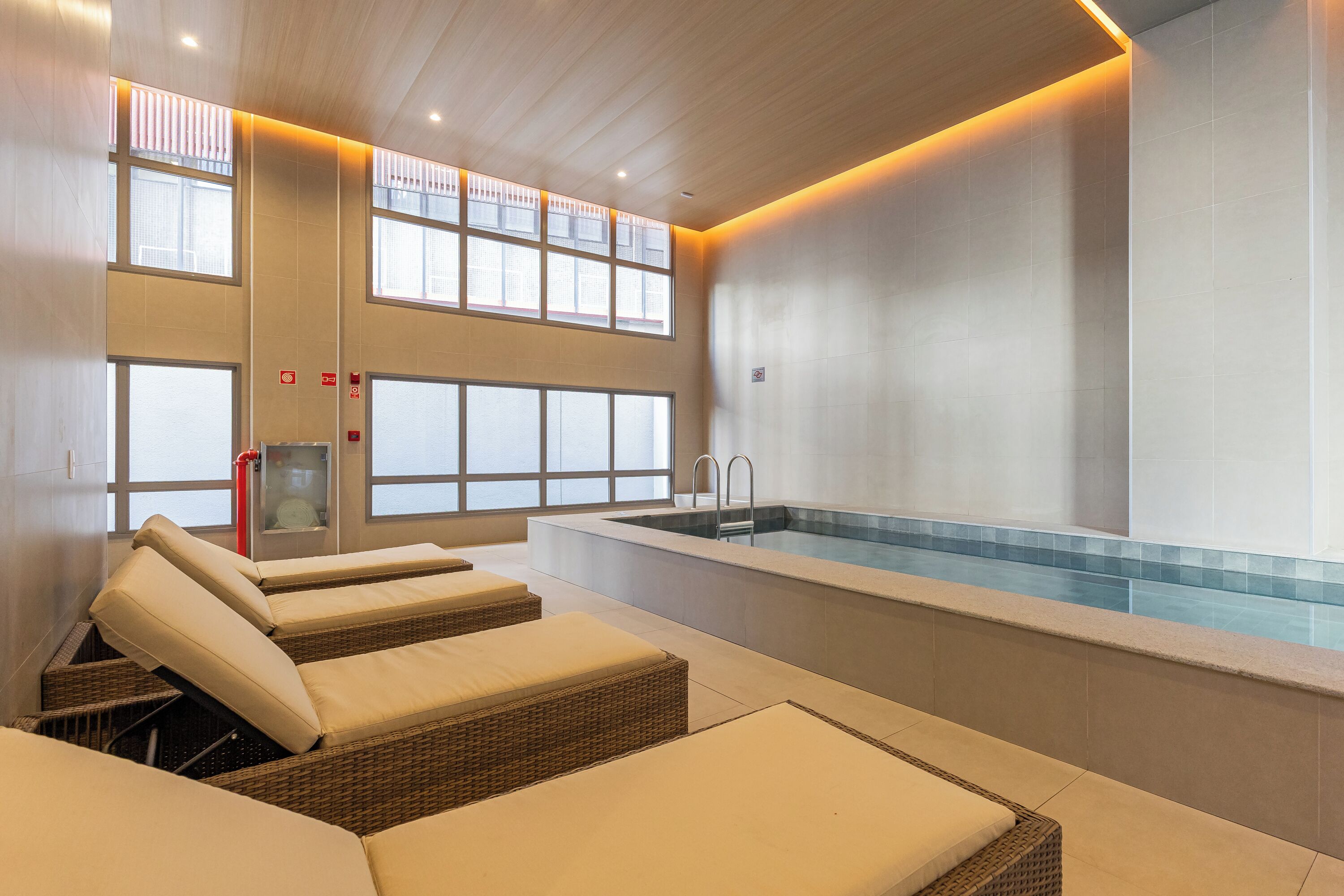 A spa area with a pool, loungers, and large windows.