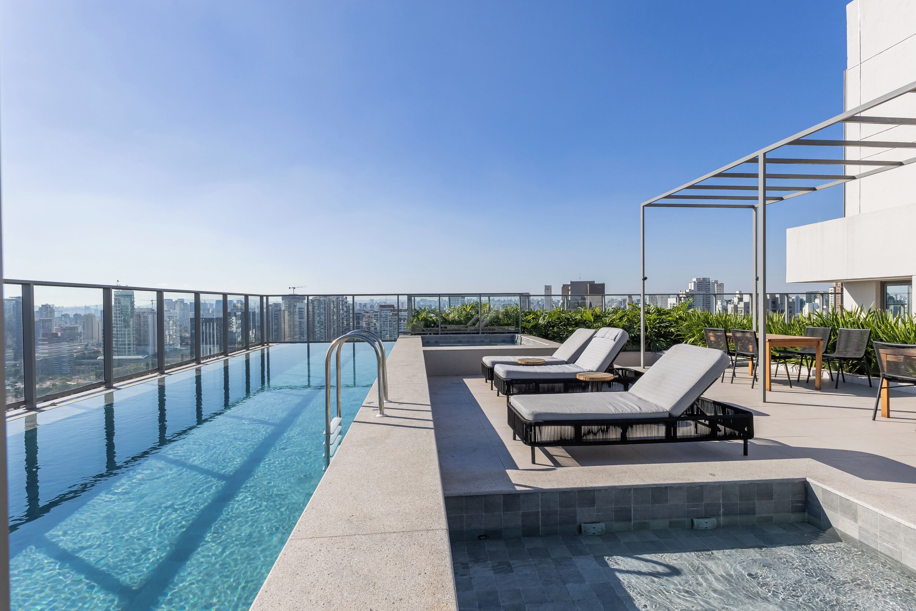 A rooftop infinity pool with lounge chairs and a view of the city skyline.