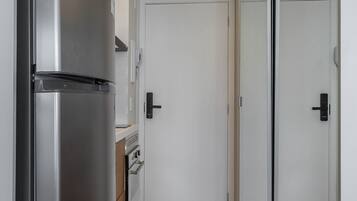 A modern kitchen with a stainless steel refrigerator, a built-in oven, and a white door.