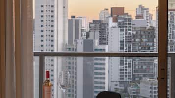 A high-rise apartment with a city view, a dining table with a bottle and a glass, and a chair.