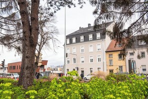 Straßenansicht mit Gebäuden, einem Baum und etwas Grün.