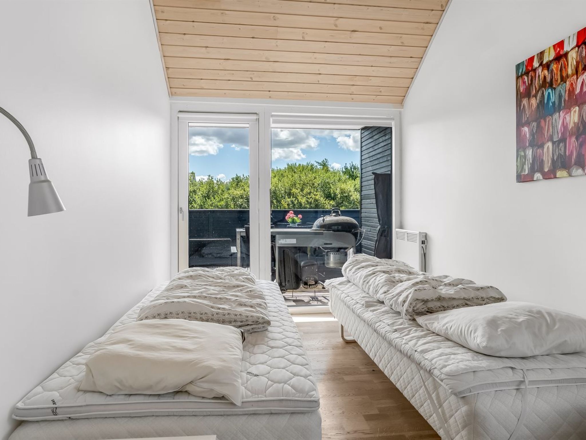 A bedroom with two beds, a ceiling fan, and a view of the outdoors.