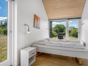 A modern bedroom with a bed, bedside lamps, a small white cabinet, and a large window offering a view of the outdoors. - "Tuva" - 3.5km from the sea by Interhome (Brovst)