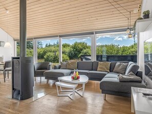 A modern living room with a large sectional sofa, a white coffee table, and a wood-burning stove. - "Tuva" - 3.5km from the sea by Interhome (Brovst)