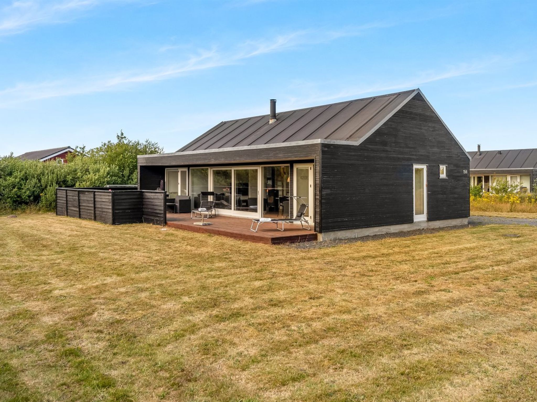 A modern house with a large deck, a covered outdoor seating area, and a well-maintained lawn.