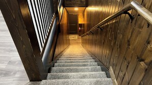 A staircase with wooden walls and a metal handrail leading to an upper floor. - Adorable 2-bedroom apartment with jetted Jacuzzi tub adjacent to Coffee Shop! (Brookfield)