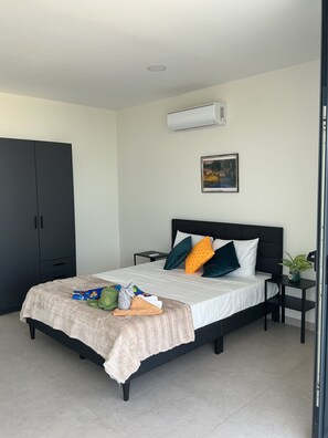 Een moderne slaapkamer met een bed, nachtkastje, kledingkast en airconditioning.