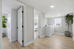 Un apartamento limpio y moderno con lavandería, una planta en maceta y vista al salón.