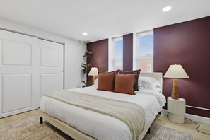 A bedroom with a bed, two bedside lamps, a window with blinds, and a door. - Beautiful 3-bedroom apartment with AC in charming St. Louis (St. Louis)