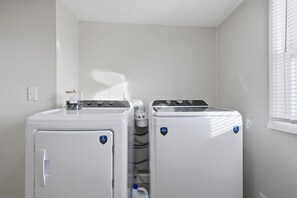 A laundry room with two front-loading washing machines and a dryer.