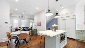 Una cocina moderna con una isla central, suelo de madera e iluminación colgante.
