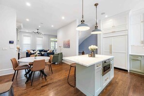 A modern kitchen with a central island, wooden flooring, and pendant lighting. - Charming Historic Row Home in Lincoln Park (Chicago)