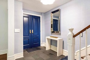 A hallway with a blue door, a white console table, and a mirror on the wall. - Charming Historic Row Home in Lincoln Park (Chicago)