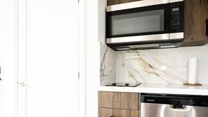 A kitchen with a microwave, dishwasher, and marble countertop. - New Vineyard Cottage in Niagara Wine Country | 2BR (Lincoln)