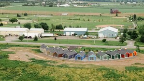 A residential area with a row of houses, a large building, and open fields. - New Vineyard Cottage in Niagara Wine Country | 2BR (Lincoln)