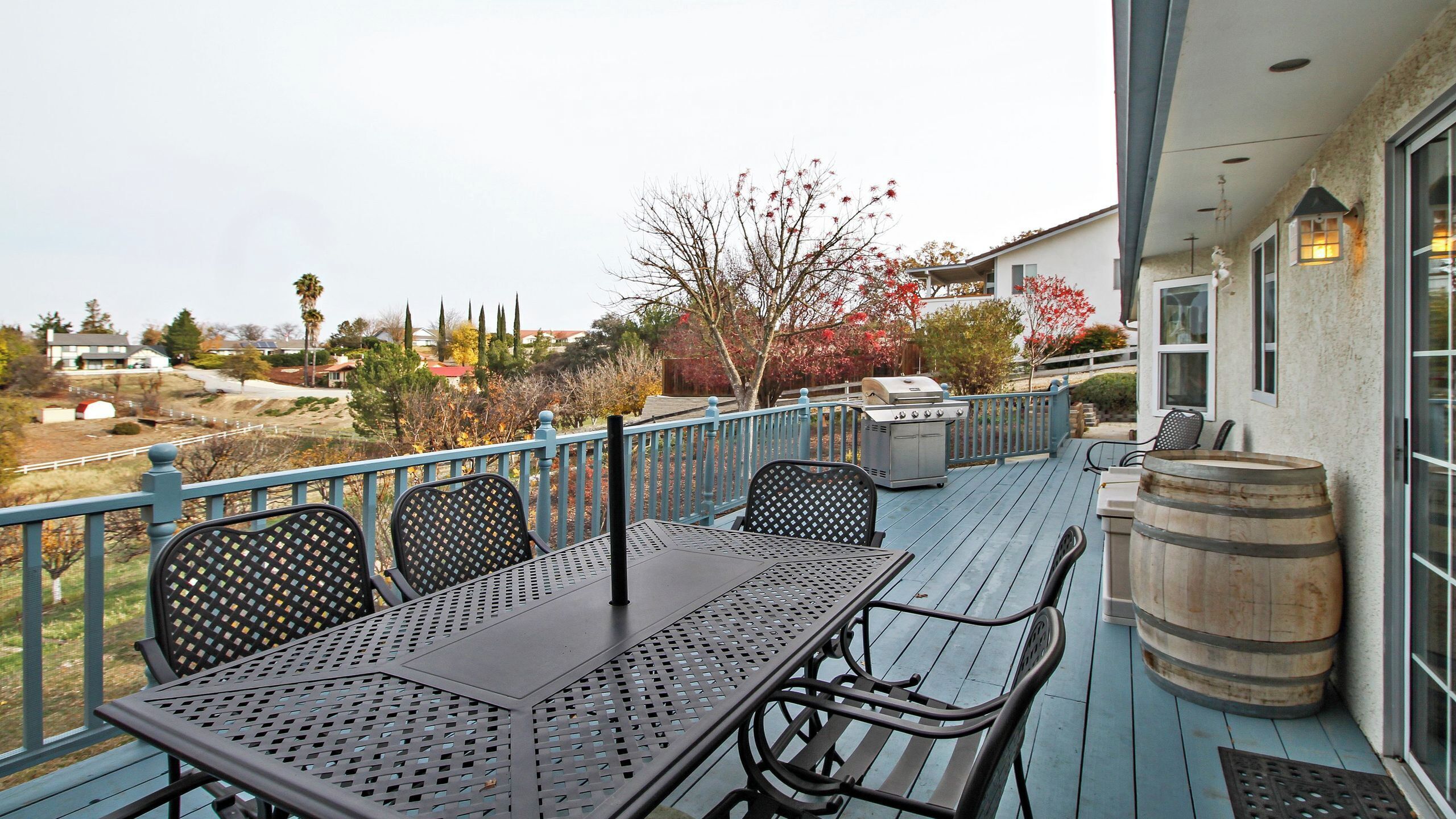 An outdoor patio with a table and chairs, a barbecue grill, and a wooden barrel.