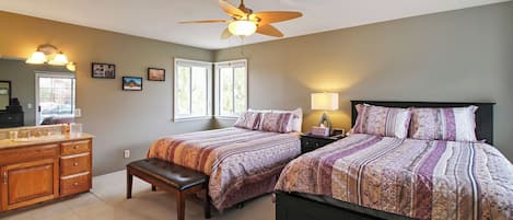 Une chambre avec deux lits, une commode, un banc, un ventilateur de plafond et une fenêtre.