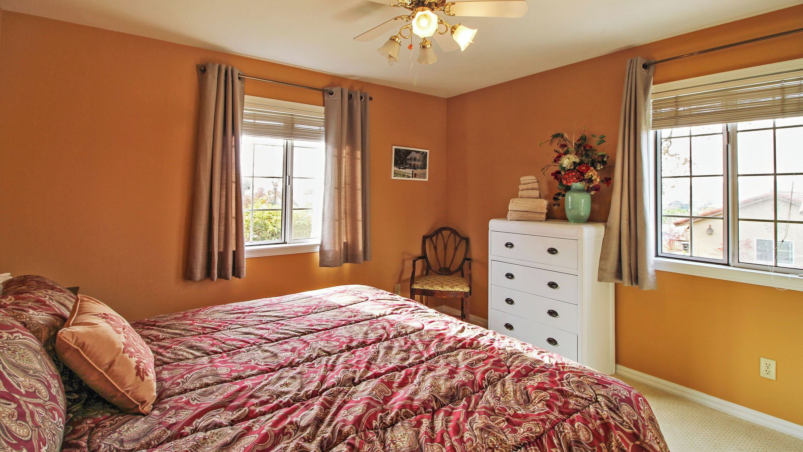 A bedroom with a bed, a dresser, a chair, and a window with curtains.