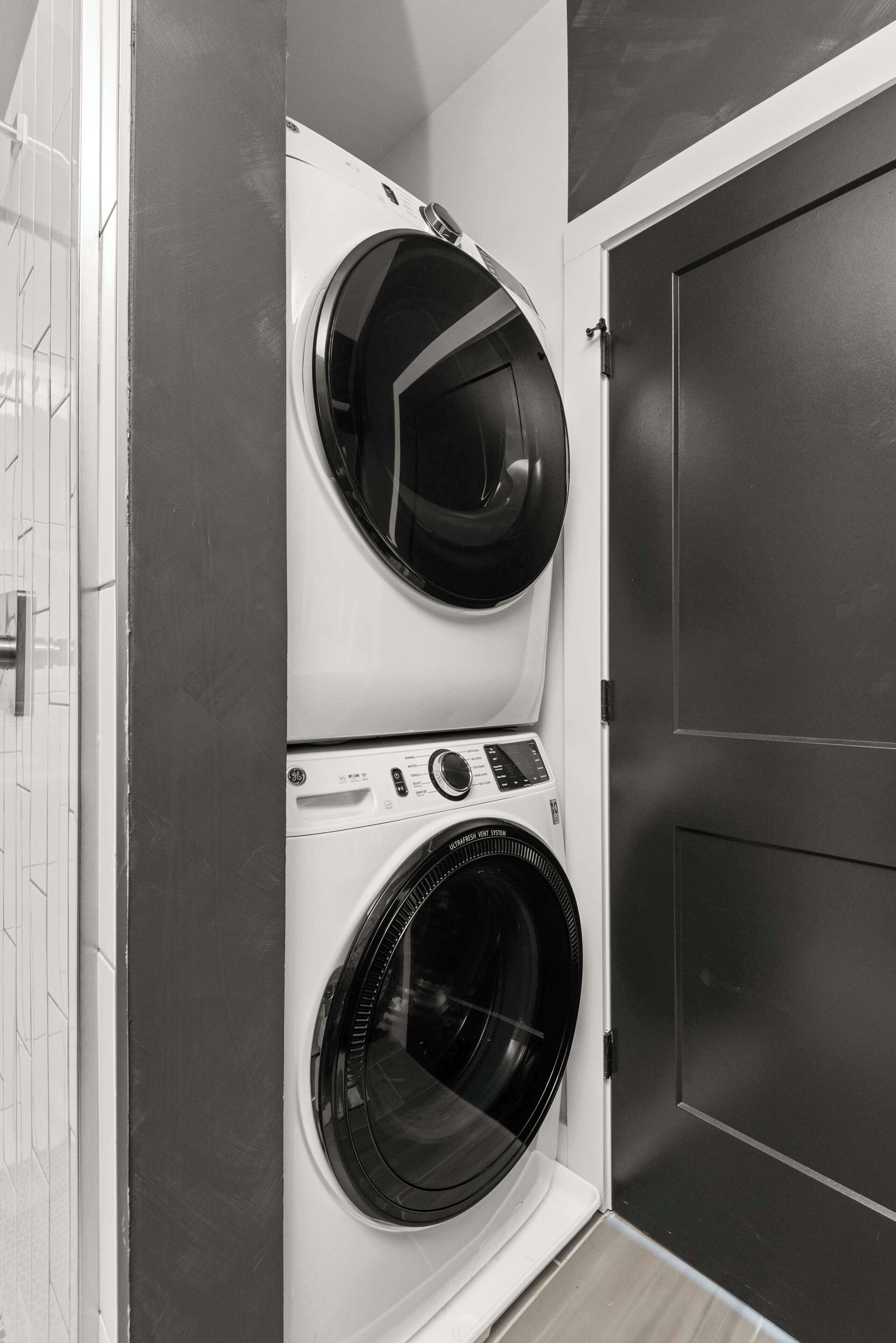 A compact laundry room with two front-loading washing machines and a door.