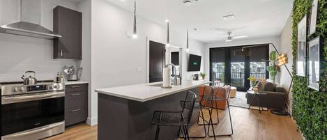 Une cuisine moderne dotée d’un îlot central, de chaises noires et d’un coin repas avec un canapé et une table.
