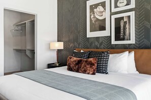 Ein Hotelzimmer mit einem Bett, einem Nachttisch, einer Lampe, einem Kleiderschrank und einer Wand mit gerahmten Bildern.